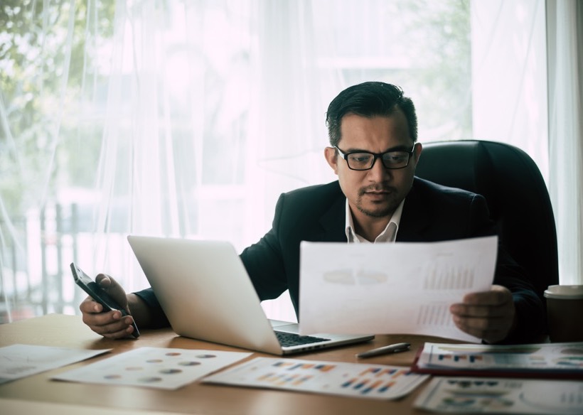 Businessman completing GST paperwork at a laptop